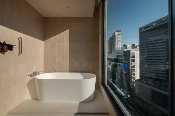 Corner Junior Suite bathroom bathtub at KROMO Bangkok with city views from Sukhumvit skyline