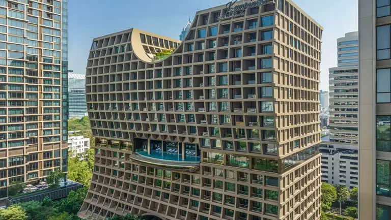 Exterior view of Sindhorn Kempinski Hotel Bangkok surrounded by lush greenery in Sindhorn Village