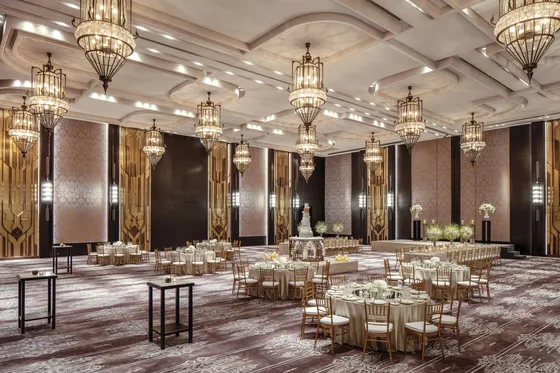 Magnolia Ballroom on Level 10 at Waldorf Astoria Bangkok, featuring a high ceiling, warm-toned interiors, textured wall panels and crystal chandeliers; the ballroom accommodates up to 700 guests