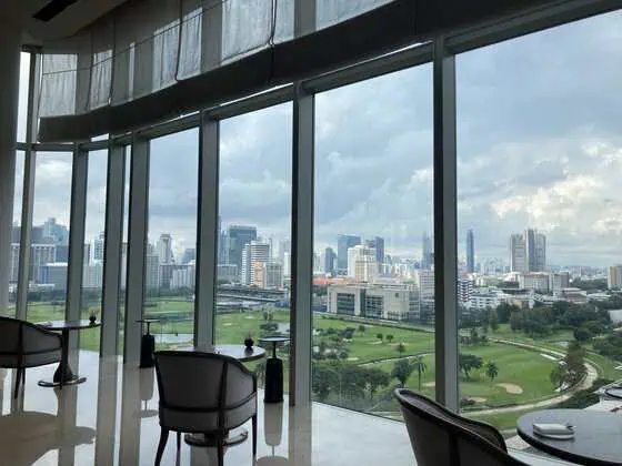 Peacock Alley at Waldorf Astoria Bangkok overlooking the Royal Bangkok Sports Club and Bangkok skyline.
